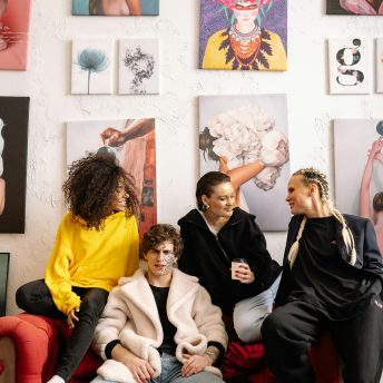 A group of young artists sit together in front of a gallery wall