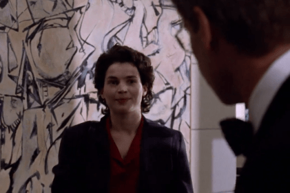 Julia Ormond in a scene from Sabrina (1995), standing before Willem de Kooning’s 1949 Abstract Expressionist painting Attic, visible in the background of a corporate interior.