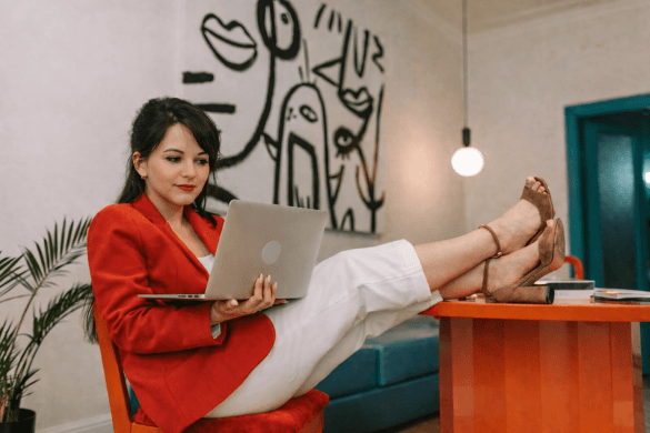 Young woman wearing red jacket sits at desk with laptop