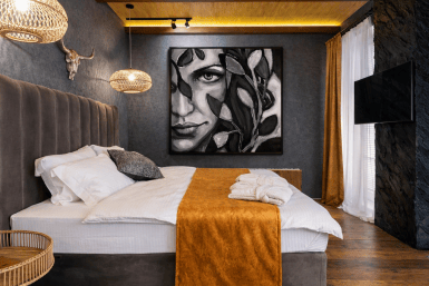 Figurative painting ‘Mina’ in monochrome noir style displayed in a contemporary rustic bedroom interior — figurative art for interiors.