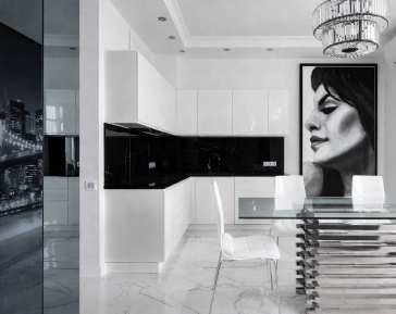 Modern white kitchen with black marble accents and a glass dining table; a large floor‑to‑ceiling framed monochrome portrait of a woman in profile (Victoria) adds a dramatic focal point on the right‑hand wall, harmonizing with the room’s minimalist palette and reflective surfaces.